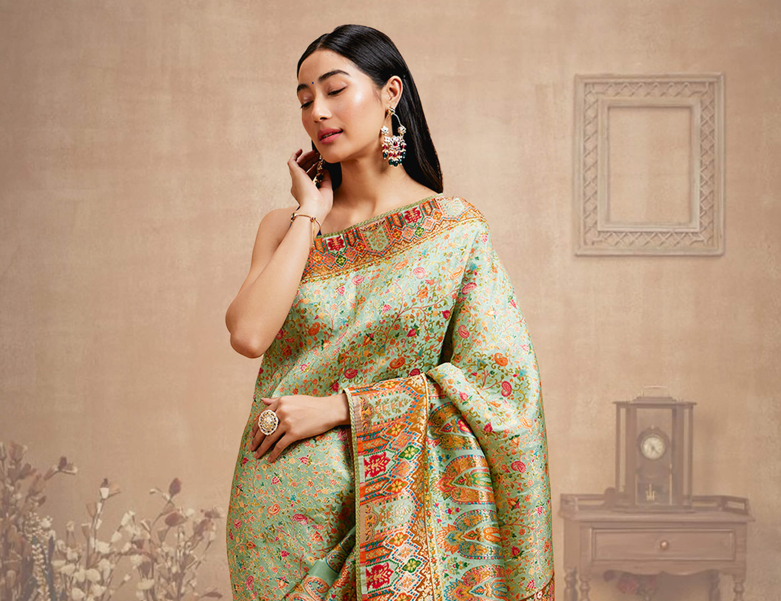 A woman wearing a silk saree and gold jewellery set